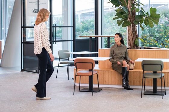 Zwei Frauen, die sich in der Empfangshalle eines Bürogebäudes für ein Gespräch treffen. | © gh